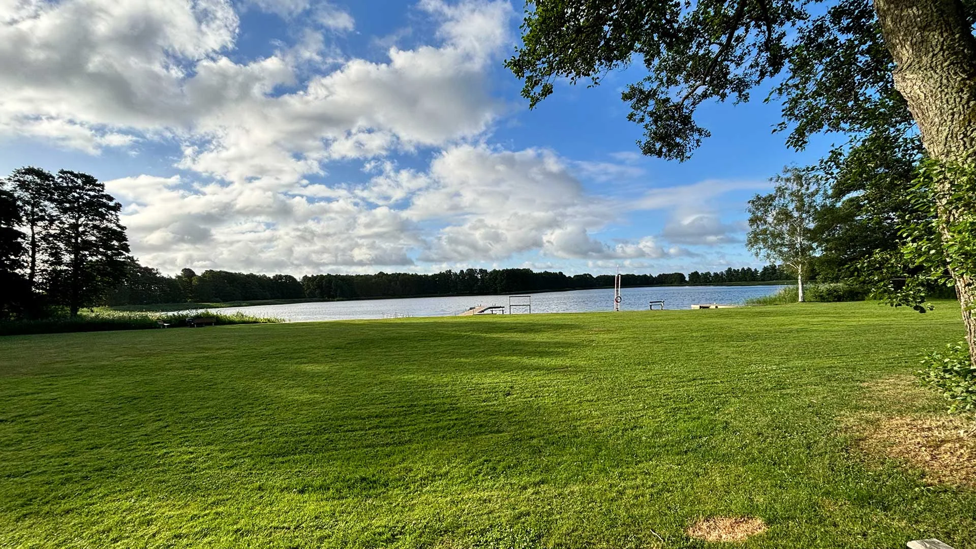 Badgäst vid en träbrygga och sandstrand vid Flämsjön vid Flämslätts badplats i Vallebygden nära Skara.