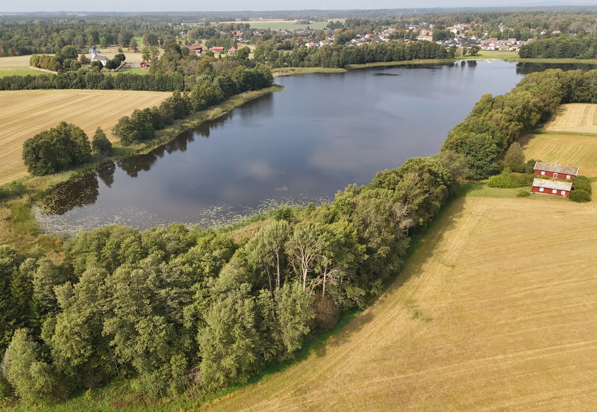 Sandstrand och brygga vid Vingsjöns badplats i Axvall, Skara kommun, en solig sommardag.