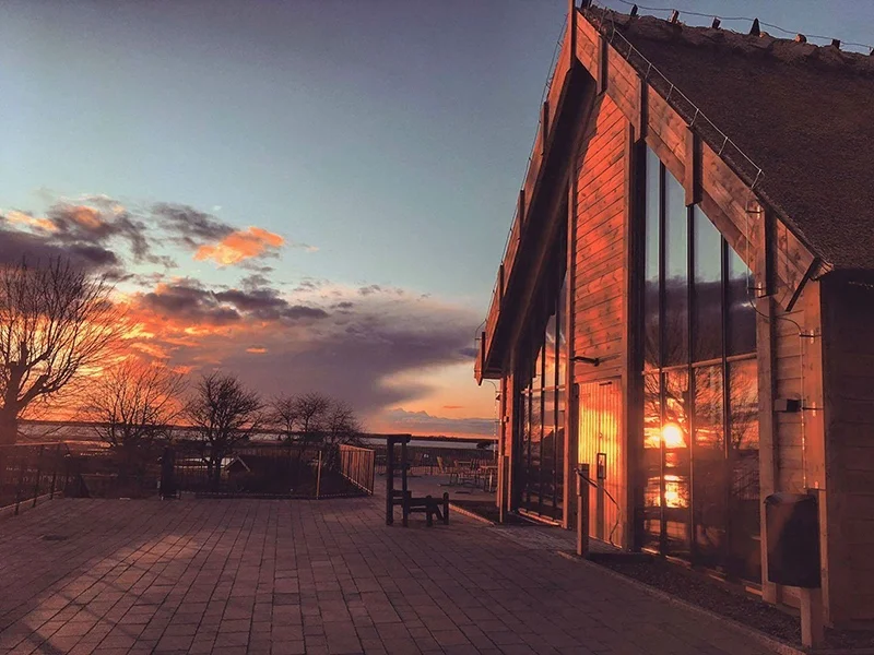 Exteriör av Café Doppingen vid Hornborgasjön i Skara med besökare som fikar i naturskön miljö.