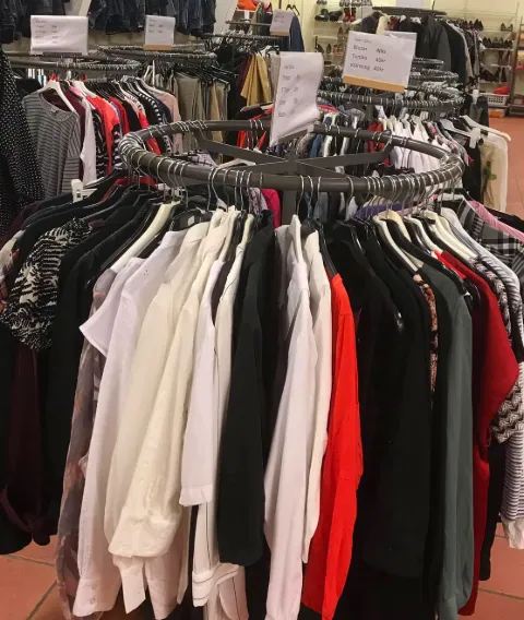 Interiör med kläder och prylar hos Kupan Second Hand i Skara, en mötesplats för hållbar shopping och återbruk.