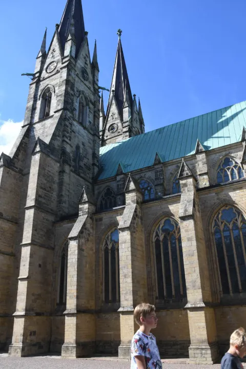 Skara domkyrka med sina två karakteristiska torn fotograferad i sommarsol under en blå himmel i Skara.