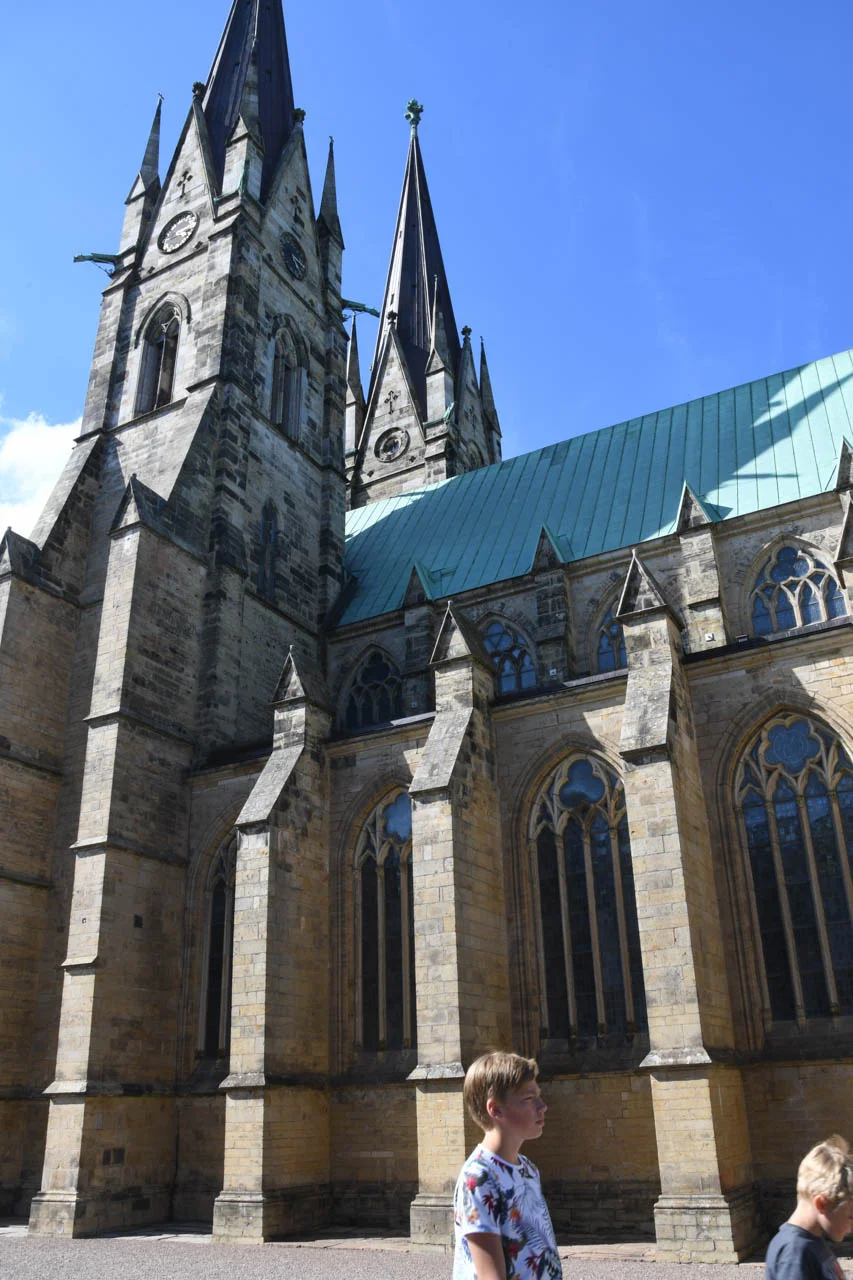 Skara domkyrka med sina två karakteristiska torn fotograferad i sommarsol under en blå himmel i Skara.