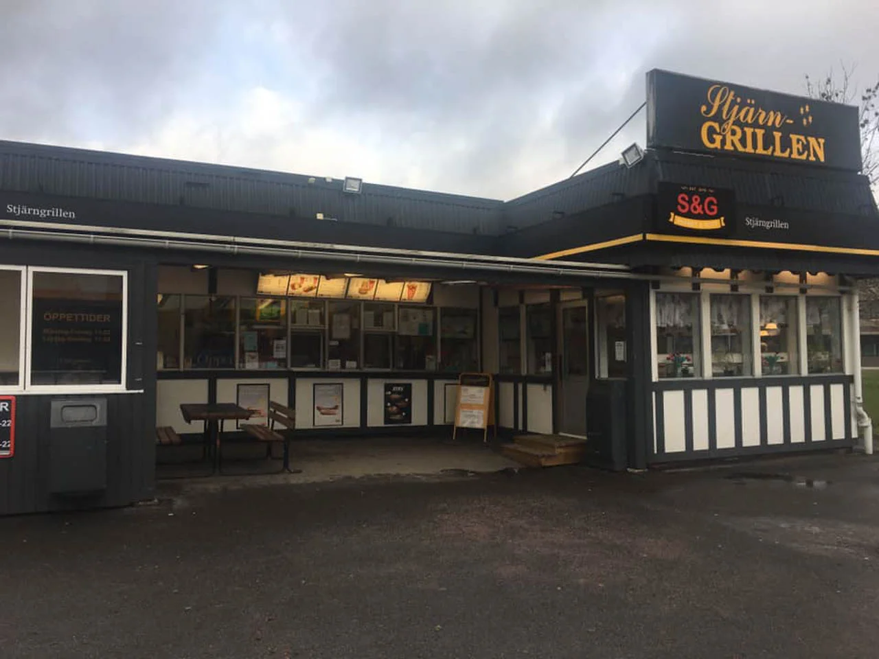 Exteriör av Stjärngrillen restaurang i Skara med skyltning och uteservering under sommaren.