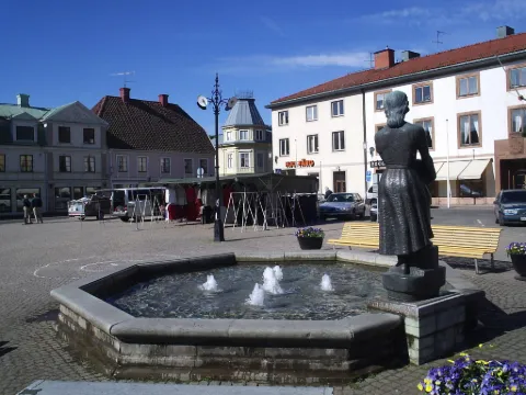 Staty framför en fontän på ett torg omgivet av äldre arkitektur.