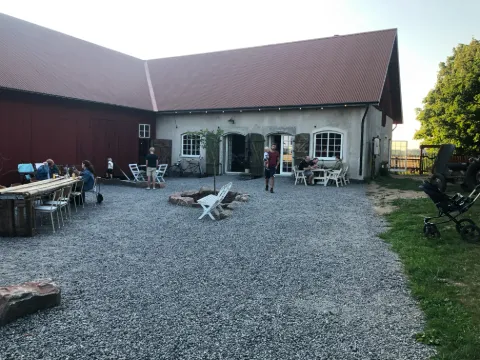 Utomhusservering vid Vedens Lustgård i Skara med bord och stolar i en grönskande trädgårdsmiljö.