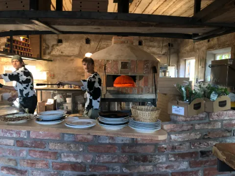 Uteservering och den röda träbyggnaden vid Vedens Lustgård i Skara under en solig sommardag.